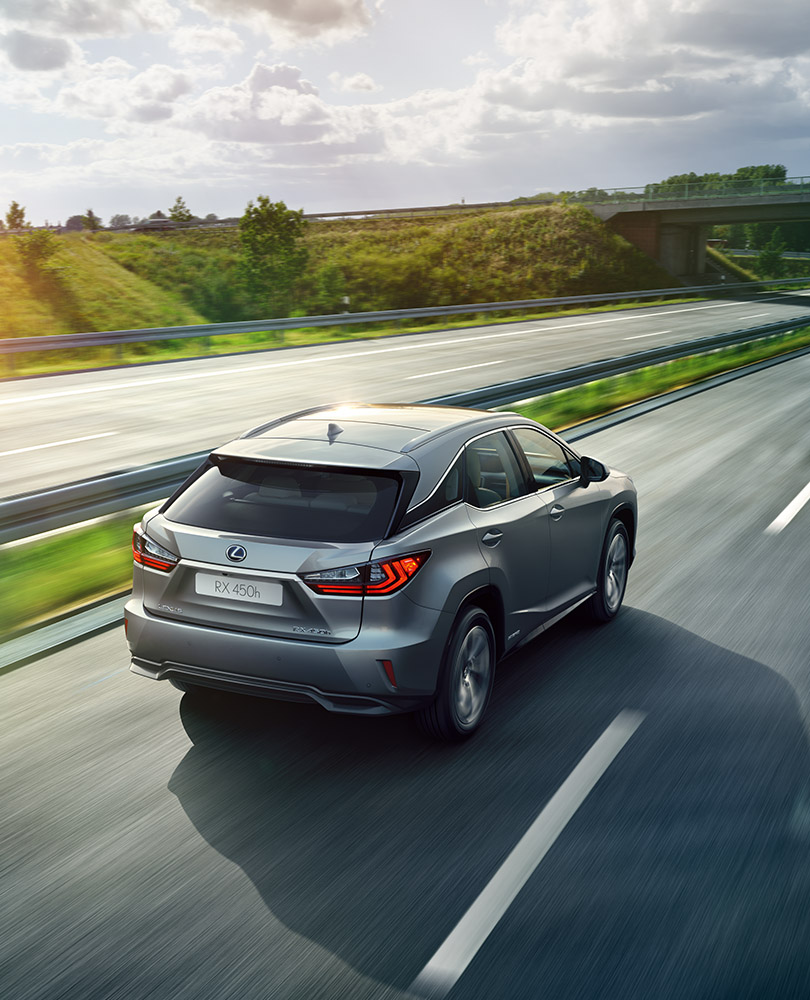 Sølvgrå Lexus SUV RX 450h selvladende hybrid kjører vekk fra oss på en motorvei